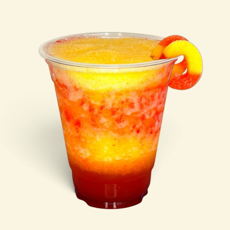 Layered orange and red fruit drink in a clear glass, garnished with a peach slice against a plain background.